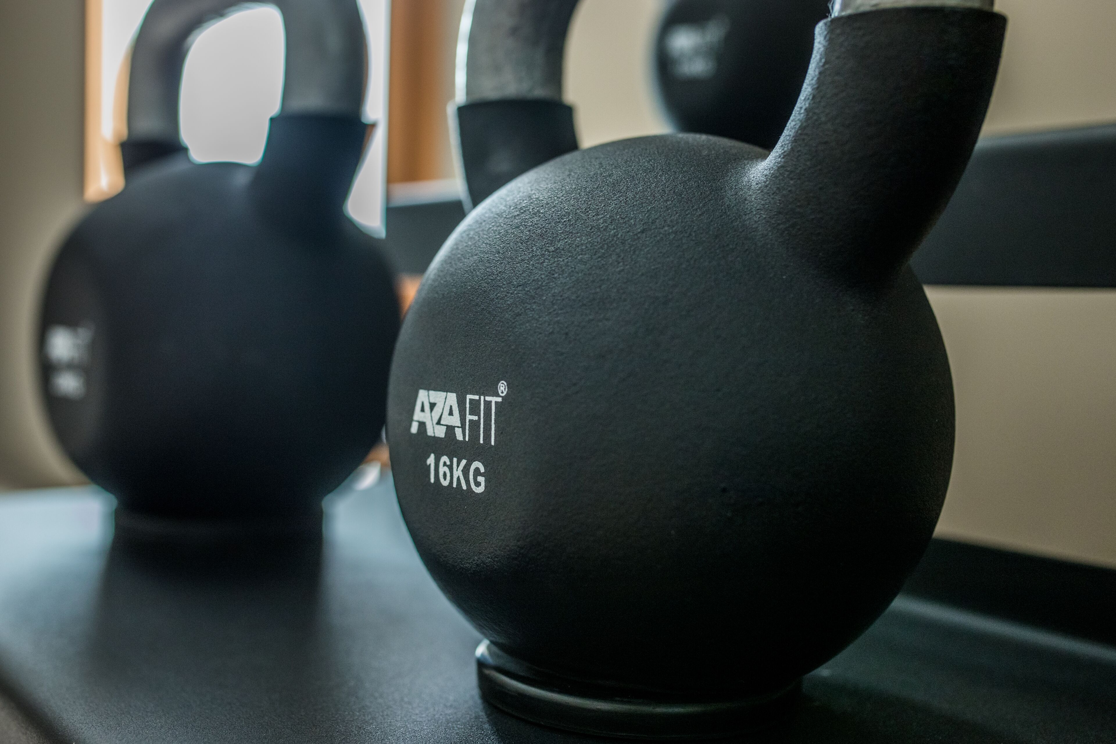 Pesas rusas con la etiqueta "AZAFIT 16KG" en equipo de gimnasio.