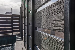 A wooden fence with horizontal slats and a metal railing.