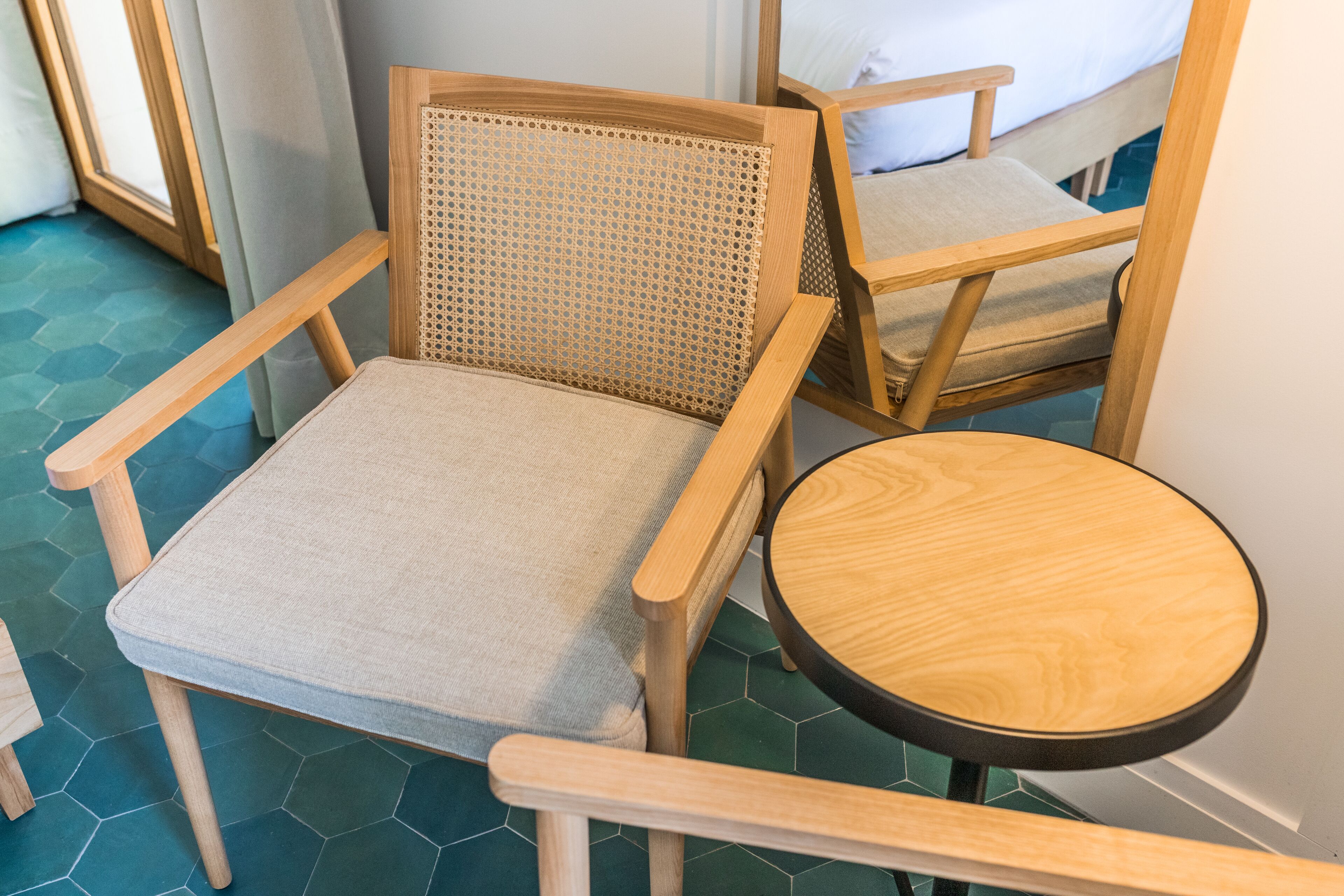 Una silla de madera con respaldo trenzado y asiento acolchado, ubicada al lado de una pequeña mesa redonda de madera.