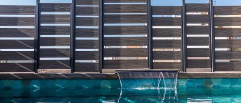 A swimming pool with a wooden fence and a hexagonal tile border.