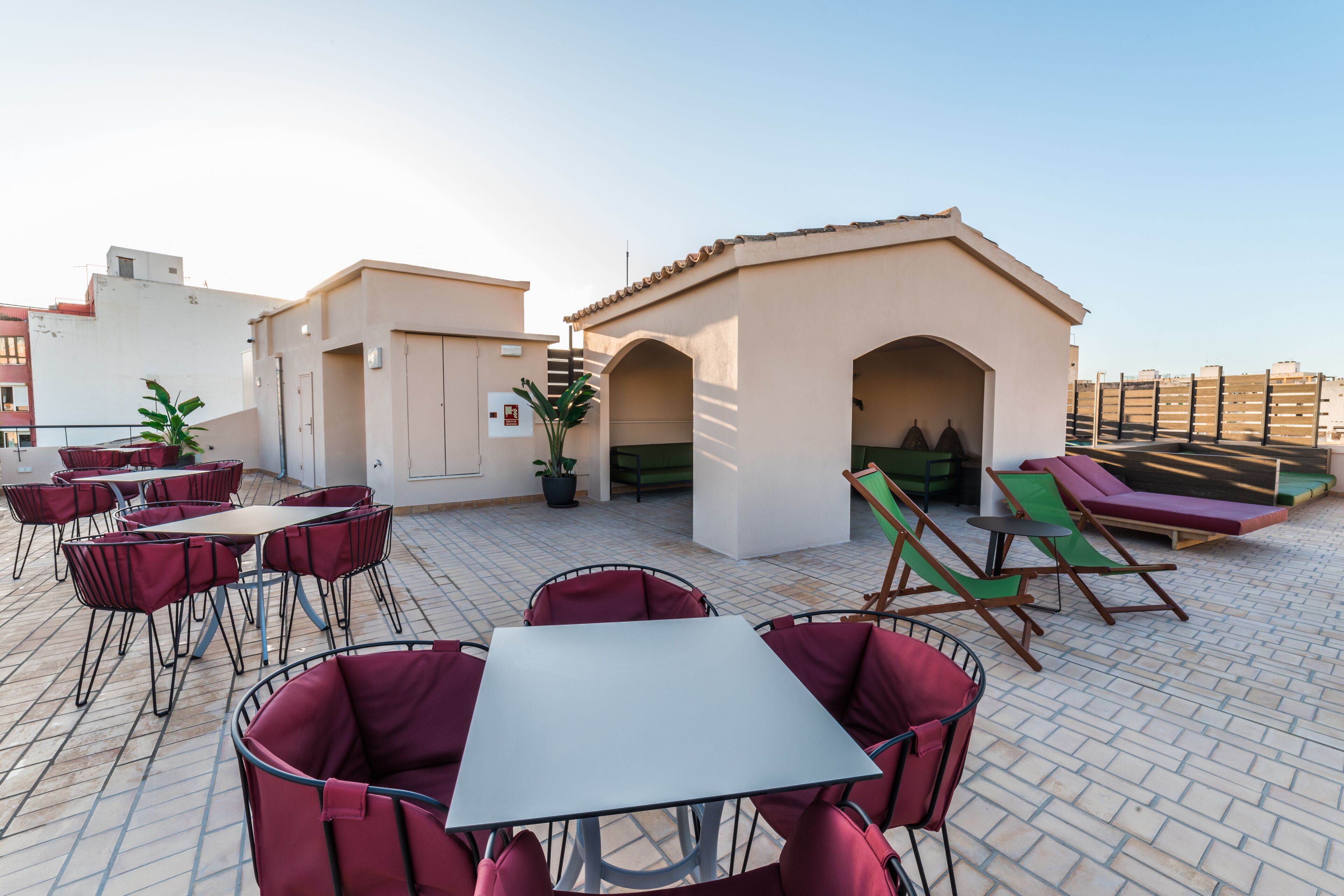 Una terraza en la azotea con mobiliario exterior, incluyendo mesas y sillas, y una pequeña construcción.