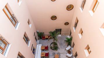 Un patio con zona de estar central, palmeras y fachada de edificio con múltiples ventanas y balcones.