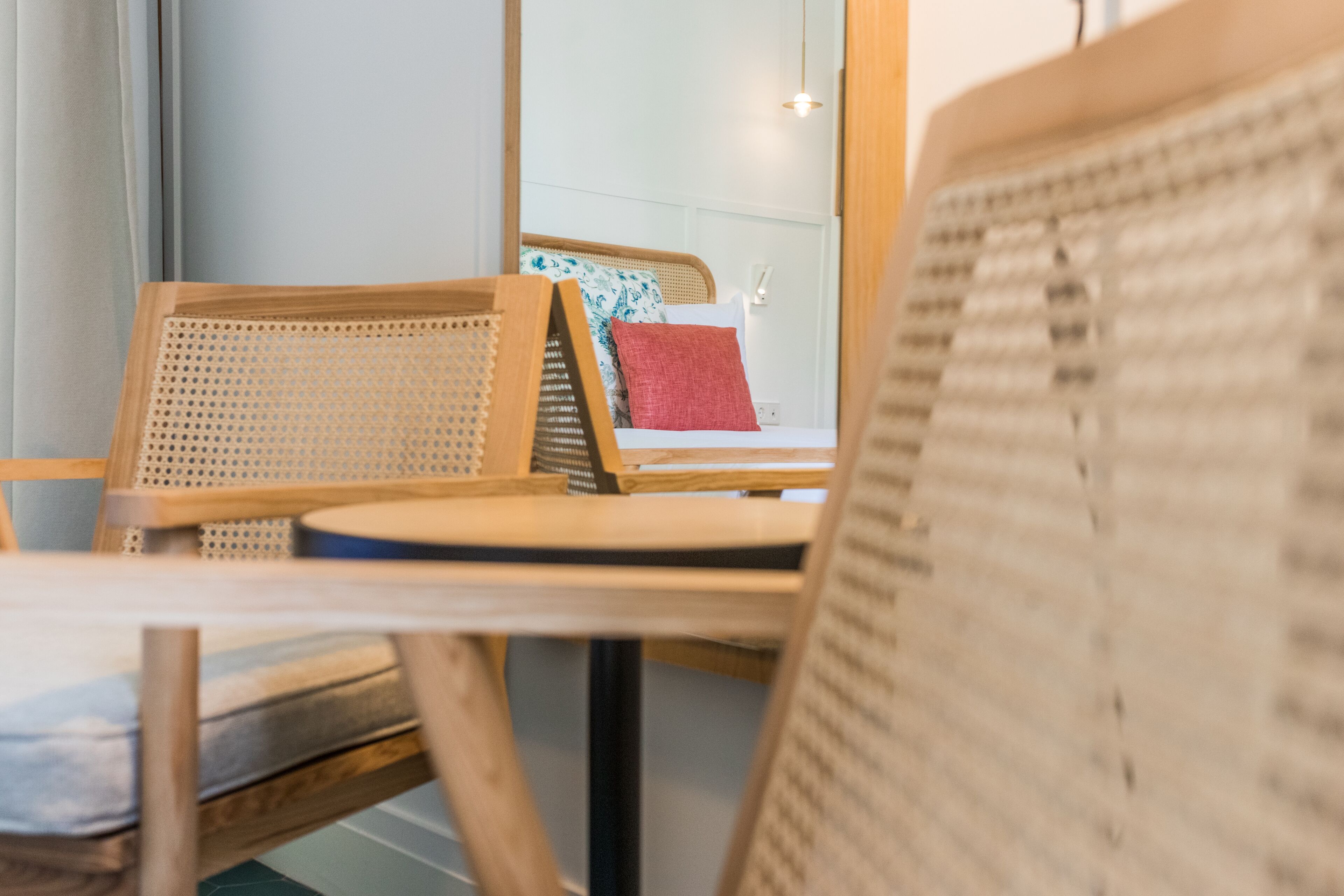 A room with a bed, a wooden chair, a table, and a window.