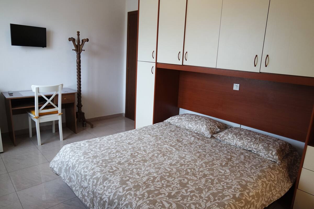 A bedroom with a bed, a desk, a chair, and a wardrobe.