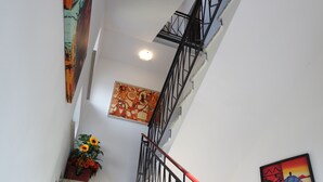 A staircase with a red handrail, a black metal railing, and a wall with a colorful abstract painting. - Le terrazze rooms (Occhiobello)