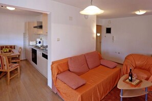 A compact living space with a kitchenette, a sofa, a dining table, and a small coffee table. - Lovely Flat with swimming pool near beach (Vinkuran)