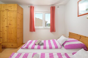 A bedroom with a bed, wooden wardrobe, and a window with curtains. - Lovely Flat with swimming pool near beach (Vinkuran)