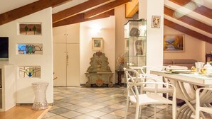 A dining area with a tiled floor, white chairs, a table with dishes, and a decorative vase. - Casa Erica (Bologna)
