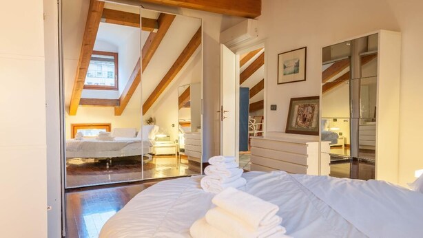 A bedroom with a large bed, a mirror, and a skylight. - Casa Erica (Bologna)