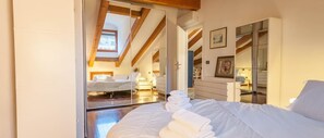 Un dormitorio con una cama grande, un espejo y un tragaluz.