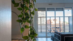 Una sala moderna con sofá, una mesa de centro y un amplio ventanal corredera que da a un balcón exterior.