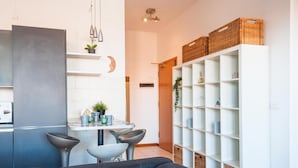 Una cocina moderna con comedor, sofá y una estantería blanca con cestas.