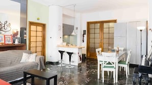 A living room with a sofa, coffee table, and a dining area with chairs and a table. - Bologna Centrale Flat (Bologna)