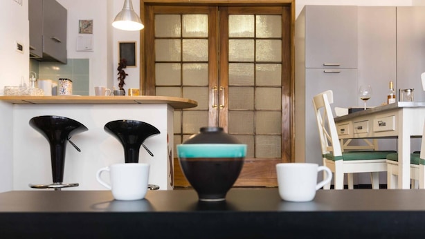 A kitchen with a marble countertop, a wooden door, and a dining area with a white chair. - Bologna Centrale Flat (Bologna)