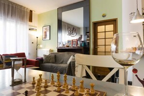 A living room with a chessboard, a glass of wine, a sofa, and a dining table.