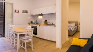 Un espace de vie compact comprenant un coin repas, une kitchenette et un lit.