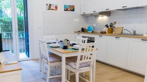 Une cuisine moderne avec des meubles blancs, un plan de travail en bois et une table à manger pour quatre personnes.