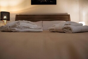 A neatly made bed with white linens and a wooden headboard. - Casa San Martino (Bologna)