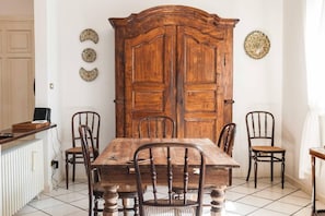 A dining room with a wooden table, four chairs, a large wooden cabinet, and three decorative plates on the wall.