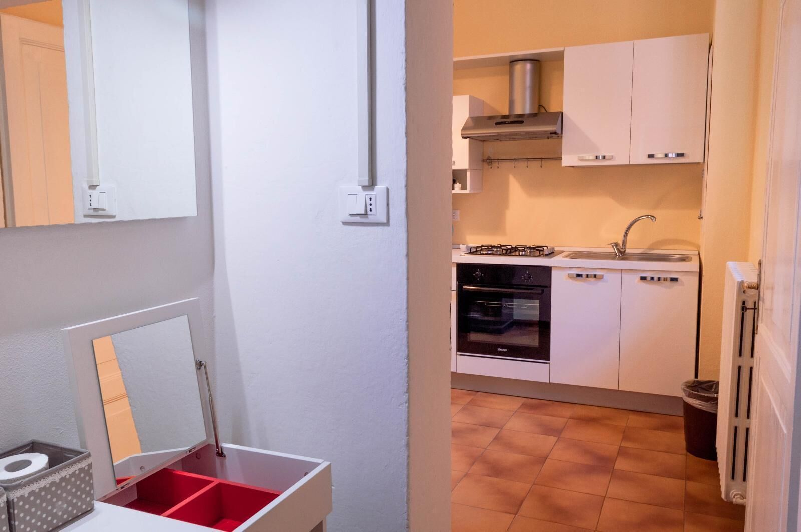 Ett kompakt kök med vita skåp, en gasspis, en ugn och ett handfat.