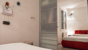 A bedroom with a bed, a red accent wall, a sliding door, and a wall-mounted light fixture. - Casa Greta (Bologna)