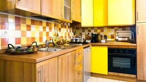A kitchen with wooden cabinets, a checkered backsplash, and a yellow accent wall. - Orange Flat - Fiera District (Bologna)