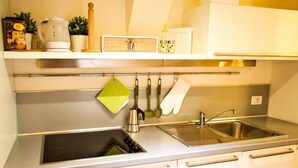 Eine moderne Küche mit Edelstahlgeräten, einer Spüle mit zwei Becken und einem Hängegestell mit Küchenutensilien.