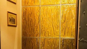 Ein Zimmer mit einer strukturierten Wandverkleidung in Goldtönen, einem gerahmten Bild an der Wand und einem Holzboden.