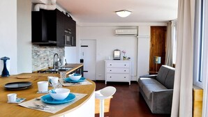 Een compacte keuken met een centraal eiland, een zithoek met een bank, en uitzicht op de omgeving.