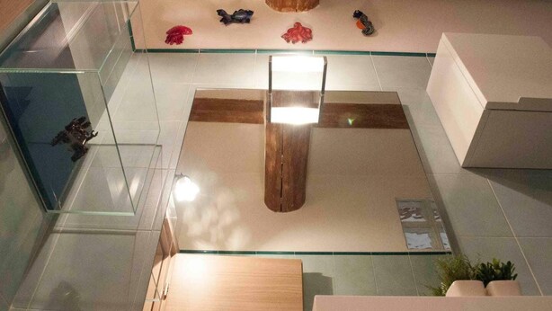 A lobby with a central wooden column, glass display cases, and a tiled floor. - Yellow Studio (Bologna)