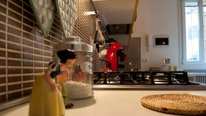 A kitchen with a large metal container labeled "SA" on the counter, a red appliance, and a woven placemat. - Yellow Studio (Bologna)