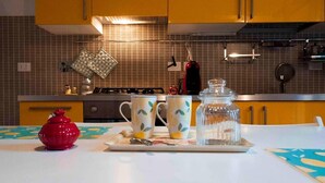 A kitchen with yellow cabinets, a gas stove, and a tiled backsplash. - Yellow Studio (Bologna)