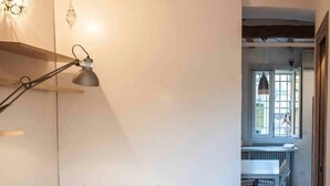 A bedroom with a bed, a bedside lamp, and a view of a dining area. - Yellow Studio (Bologna)
