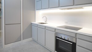 Eine moderne Küche mit weißen Schränken, einer Edelstahlspüle und einem Backofen.