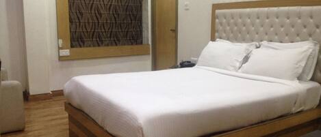 Una cama bien tendida con cabecera acolchada en una habitación de hotel.