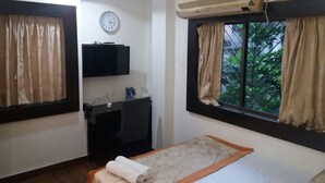 A hotel room with a bed, a desk, a television, and an air conditioning unit. - Ashreen Guest House (Kolkata)