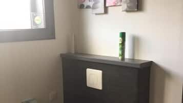 A small bathroom with a toilet, a towel rack, and a window.