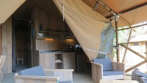 Un espace de cuisine extérieur aménagé sous une tente, avec des meubles en bois et une table à manger.