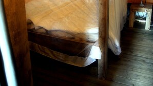 Un lit à baldaquin en bois, une table de chevet avec une lampe et une fenêtre avec des rideaux.