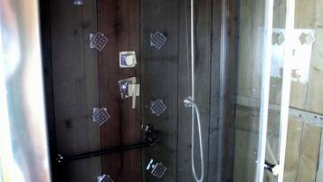 A glass-enclosed shower with a wooden interior, a handheld showerhead, and a wall-mounted control panel.