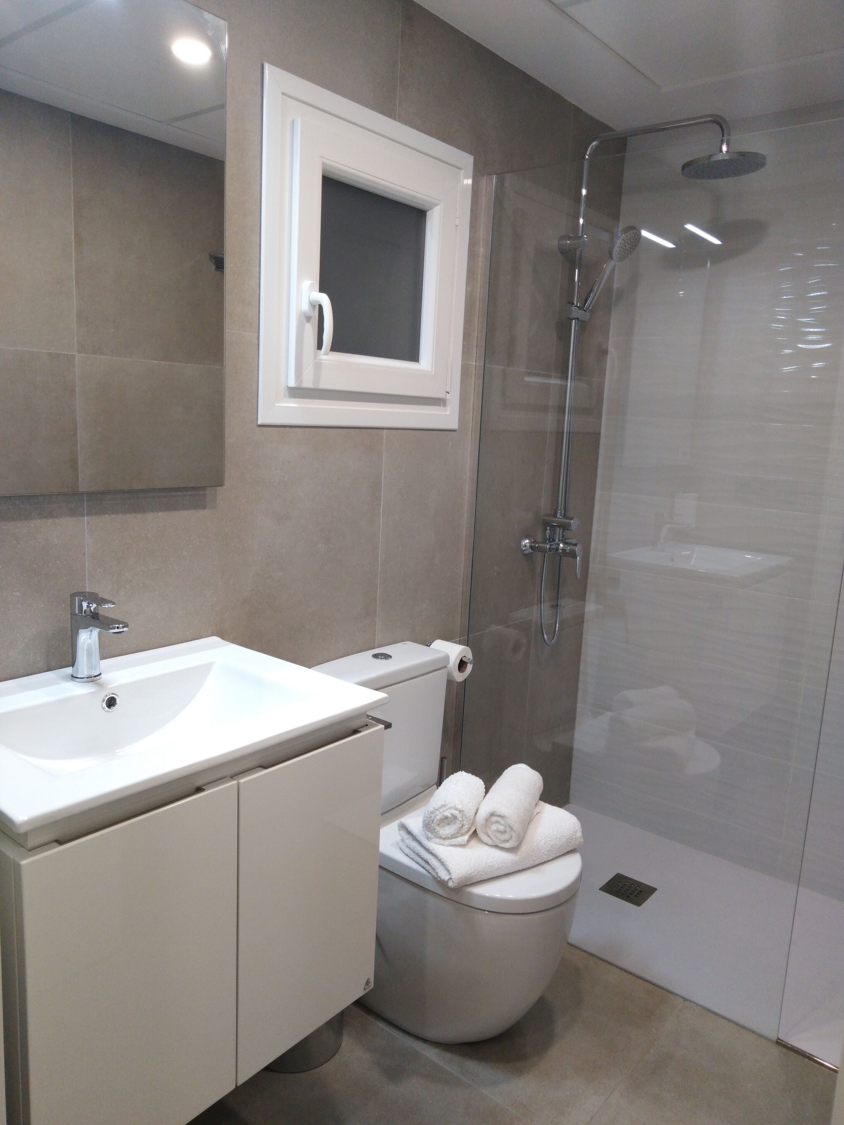 A modern bathroom with a white sink, toilet, and shower.