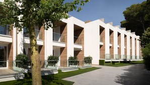 Een modern gebouw met een symmetrische gevel, grote ramen en een centrale binnentuin met een boom.