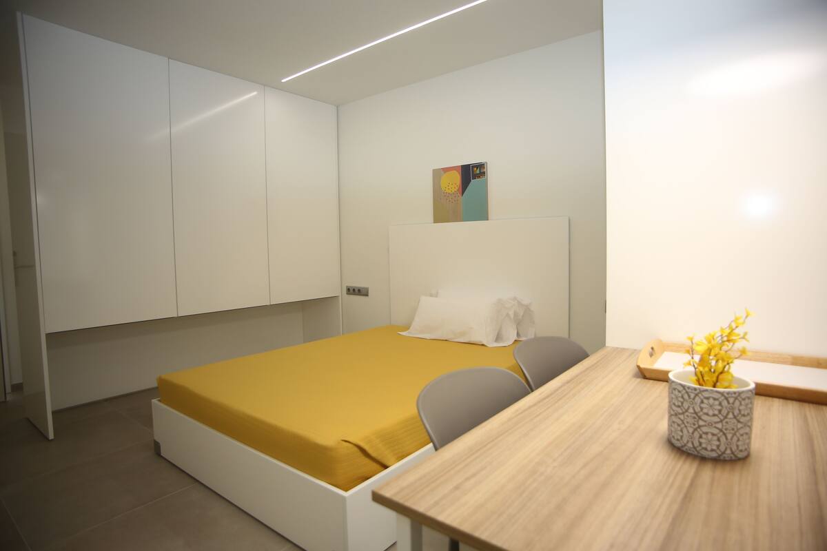 Een moderne slaapkamer met een bed, een bureau en een stoel.