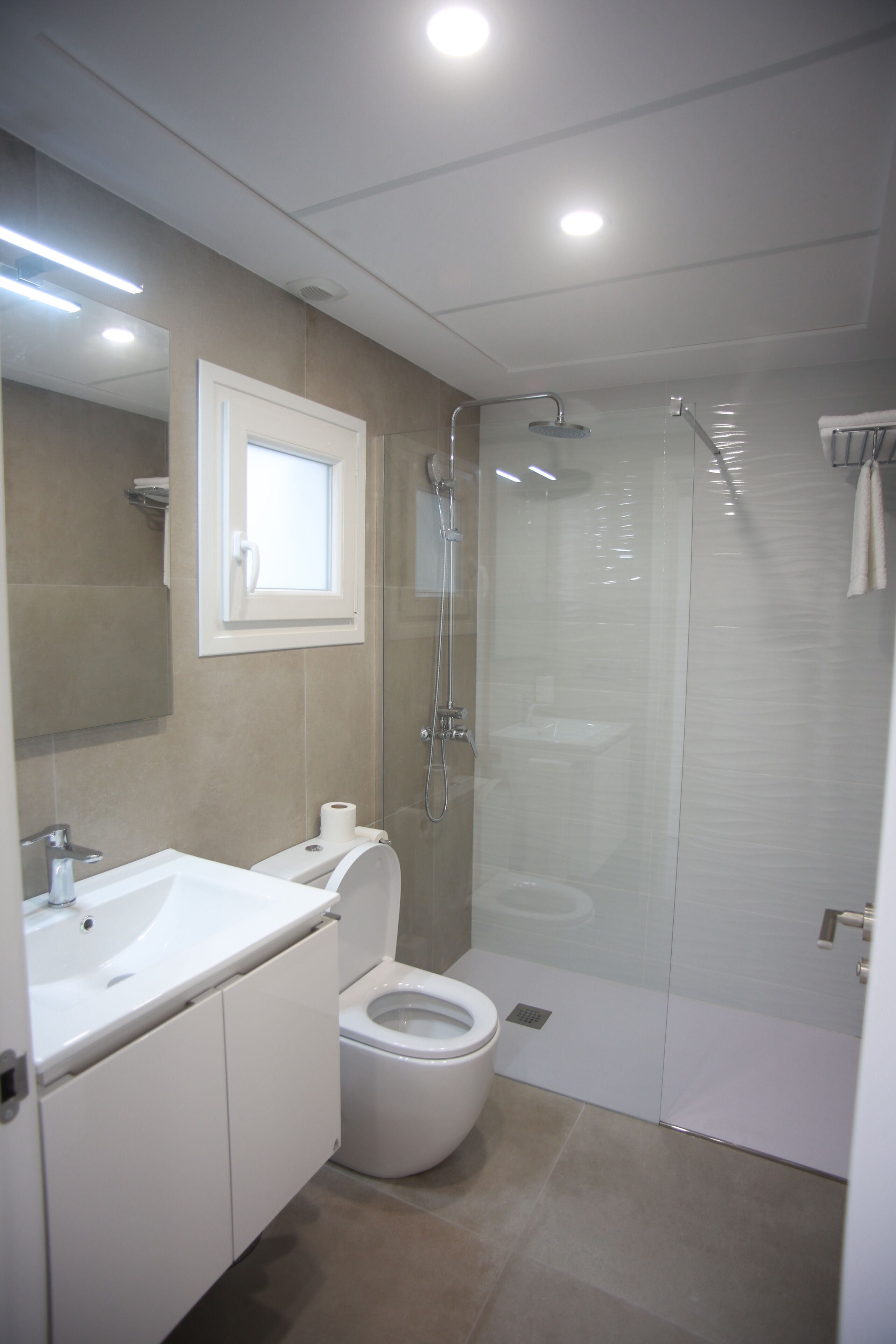 Un bagno moderno con doccia vetrata, lavandino bianco e WC.