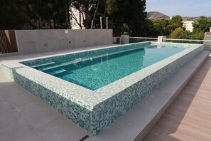 Una piscina al aire libre, sombrillas, tumbonas