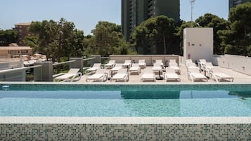 Una piscina al aire libre, sombrillas, sillones reclinables de piscina