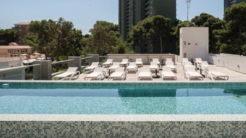 Una piscina al aire libre, sombrillas, tumbonas