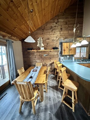Cozy dining area with a long table and six chairs, surrounded by rustic charm and natural ambiance.