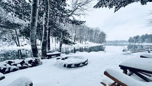 Area esterna innevata con tavoli da picnic e una panchina in legno.