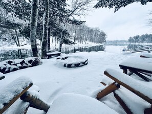 Escape to a serene winter wonderland surrounded by snow-covered trees and a tranquil body of water.